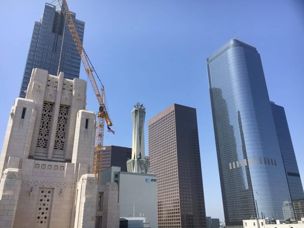 A view of several modern skyscrapers and a construction crane under a clear blue sky in an urban city center, reminiscent of the vibrant atmosphere near some of the Best Boutique Hotels in Los Angeles.