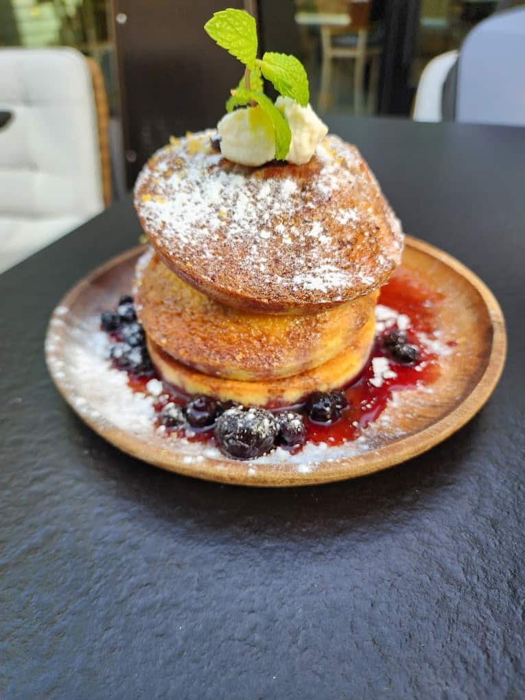 The best breakfast in San Francisco, featuring a stack of pancakes topped with blueberries and powdered sugar.