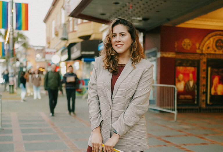 A woman wearing a blazer and a burgundy dress, showcasing a stylish ensemble for what to wear in San Francisco.