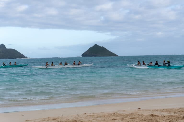 A group of couples in canoes enjoying one of the many things to do in Oahu on a beautiful beach.