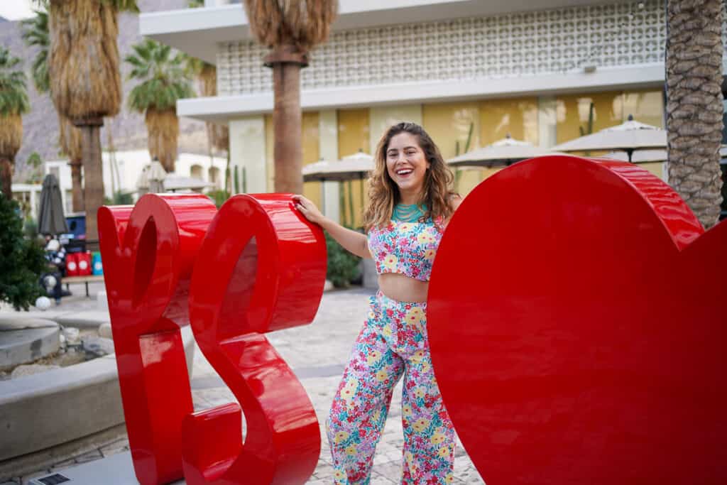 A woman posing in front of a large heart shaped sign, perfect for Instagram captions to boost engagement.