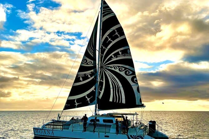 "Things to do in Oahu for Couples: Sail on a catamaran in the ocean with a black and white sail.