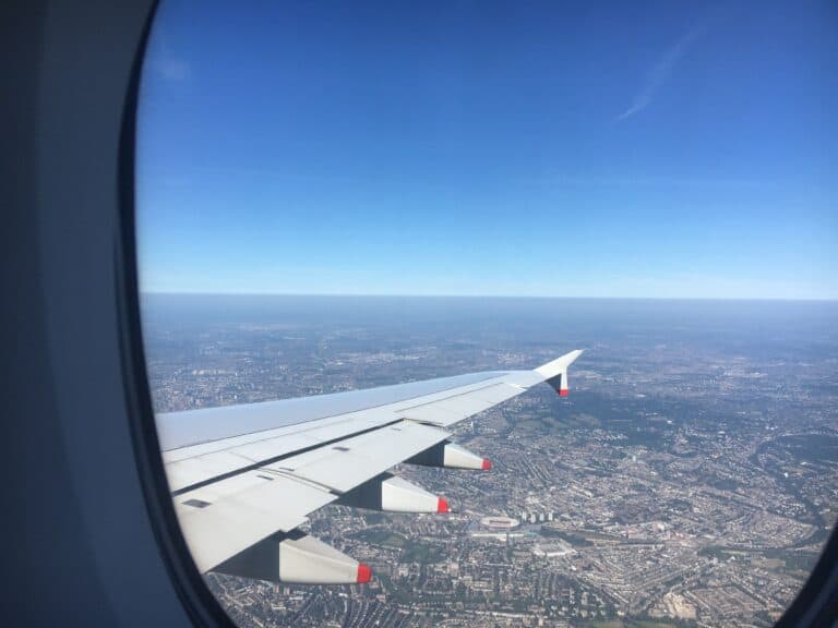 Aerial view of a cityscape through an airplane window with a wing in sight, showcasing things to do near LAX.