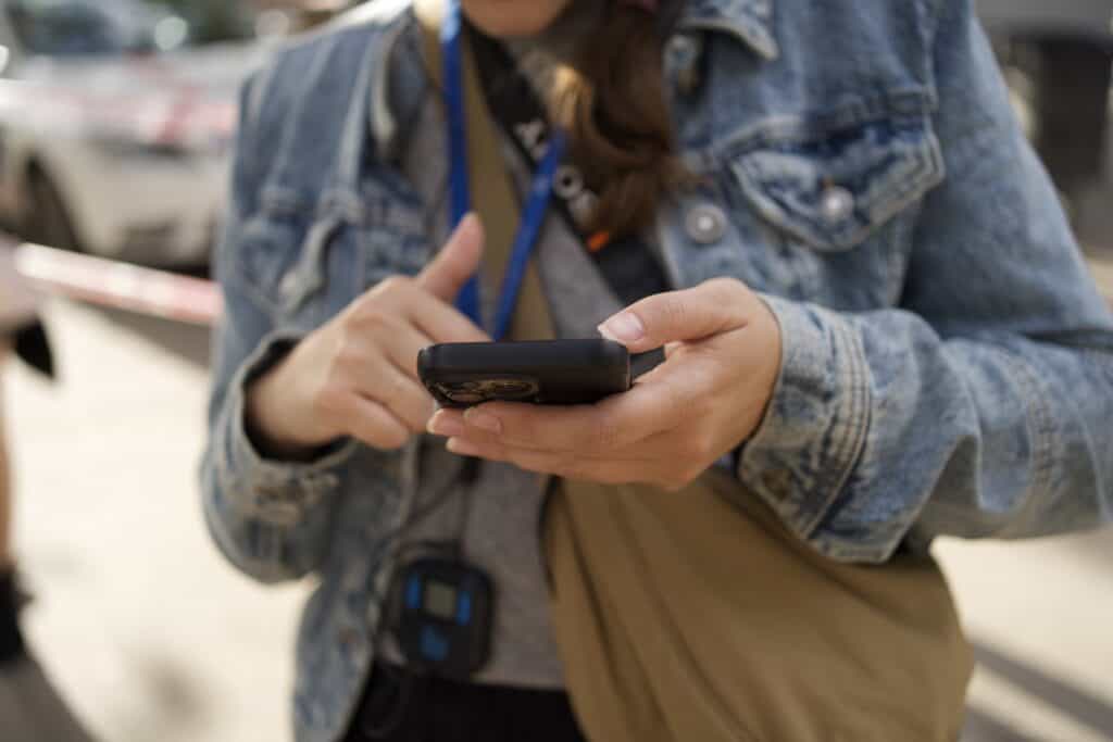 A person sporting a denim jacket uses a smartphone outdoors, effortlessly staying connected with eSIMs for digital nomads.
