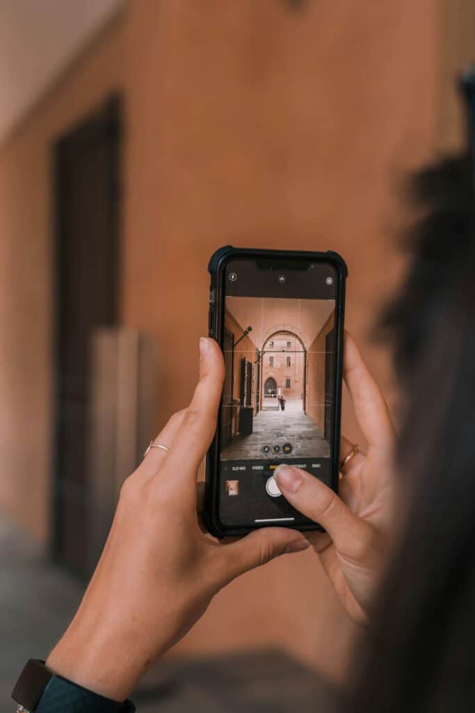 A digital nomad captures the charm of an arched hallway with their smartphone, highlighting the seamless convenience of eSIMs for globetrotters.