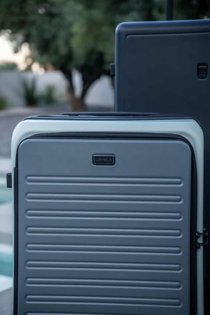 Two hard-shell suitcases, one gray and one dark blue, positioned upright outdoors near a pool with trees in the background—ideal for a Level8 luggage review in a stylish travel setting.