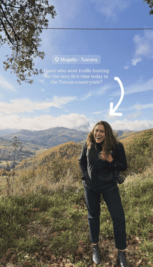 A woman stands smiling outdoors in front of rolling hills and trees under a partly cloudy sky in Mugello, Tuscany. Text and an arrow label her as having tried truffle hunting in Tuscany for the first time.