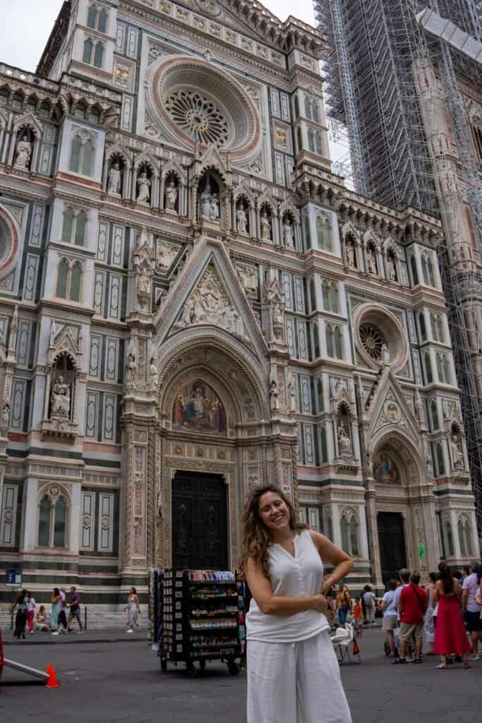 A smiling woman stands in front of the ornate facade of the Cathedral of Santa Maria del Fiore, a highlight for any 3 days in Florence.