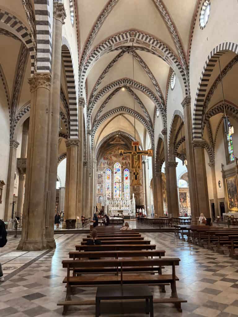 Interior of a large Gothic church with rows of wooden pews, high arched ceilings, and a central crucifix, often visited during 3 days in Florence.
