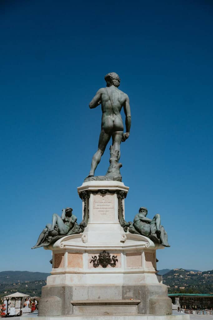 A bronze sculpture of David seen from behind atop a stone pedestal, a highlight to include in a 3 days in Florence itinerary.