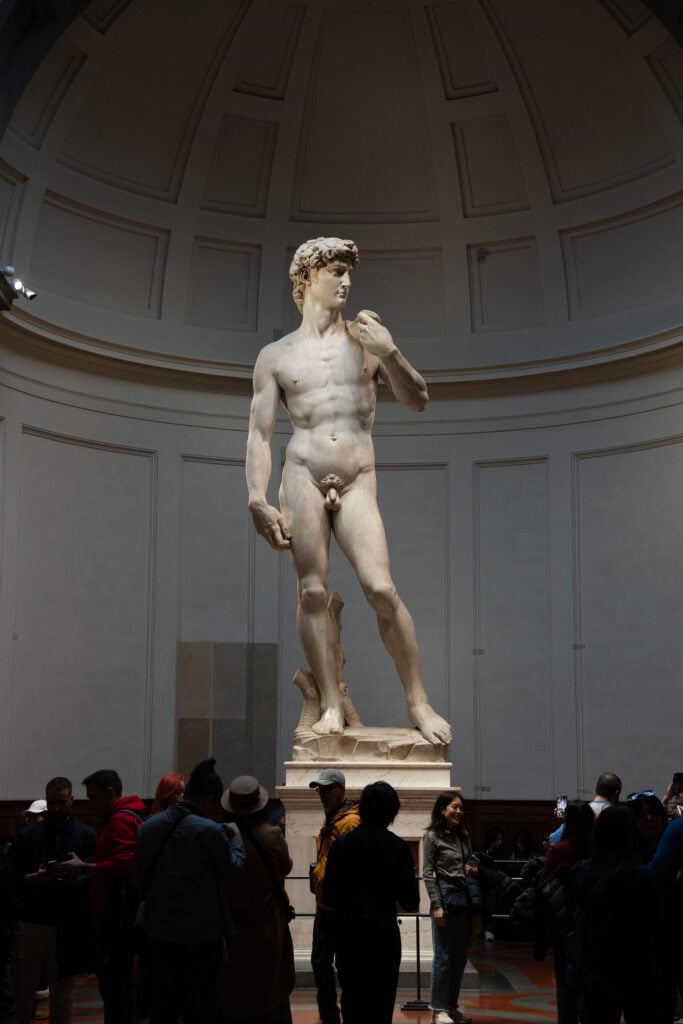 Michelangelo’s marble statue of David on a museum pedestal, surrounded by a crowd of visitors during a 3 days in Florence itinerary.